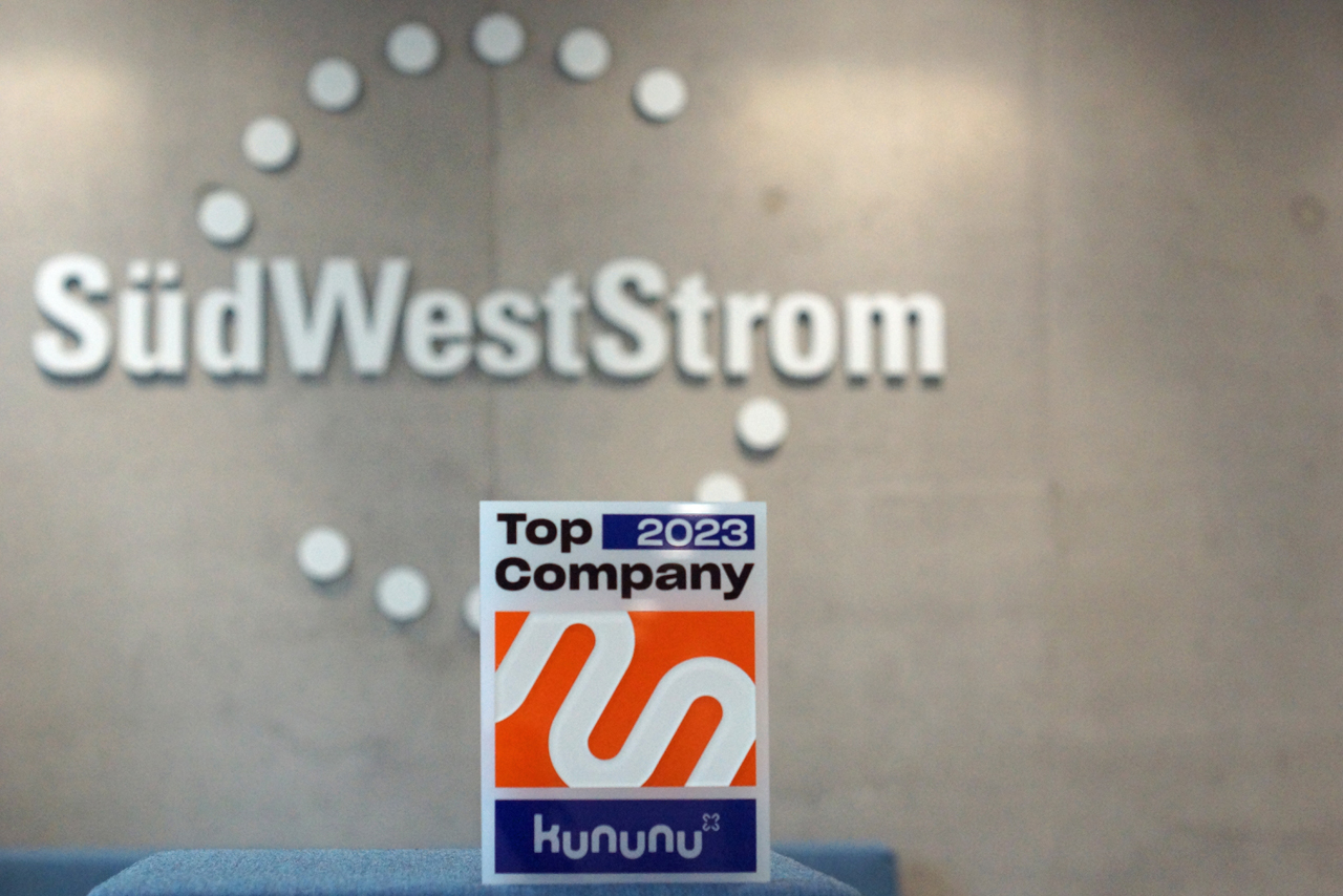 Auszeichnungs-Schild von kununu vor dem SüdWestStrom-Logo im Hintergrund